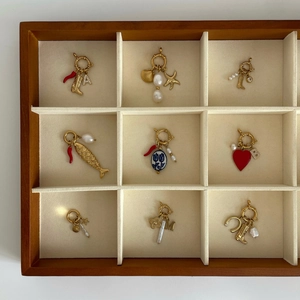 Collection de charms vintage dorés avec perles, cœurs et étoiles dans un coffret en bois