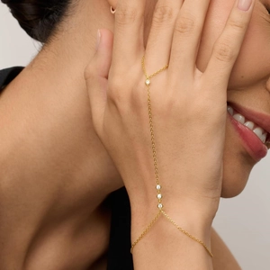 Close-up of a 18K gold plated hand chain with four bezel-set round sparkling zircons