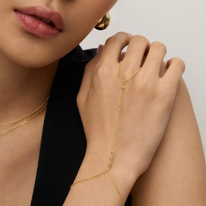 Macro detail of gold-plated slave bracelet with polished beads on female hand