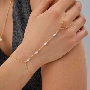 Detail of gold finger bracelet featuring five oval pearls on a delicate chain