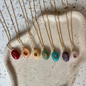 Detail view of seven colorful water drop pendants on 18k gold plated titanium necklaces