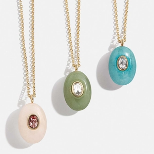 Detailed view of three teardrop-shaped natural stone necklaces in pink, green, and blue colors