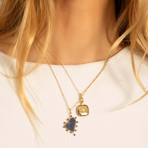 Close-up of layered gold necklaces featuring a blue heart pendant and a square locket