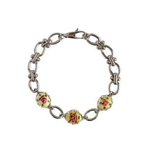 Détail d'un bracelet à chaîne argentée avec trois pendentifs ovales en émail rose