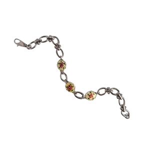 Détail d'un bracelet gourmette rétro en argent avec pendentifs floraux en émail rose