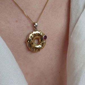 Close-up of donut pendant necklace with colorful zircon stones and gold plating