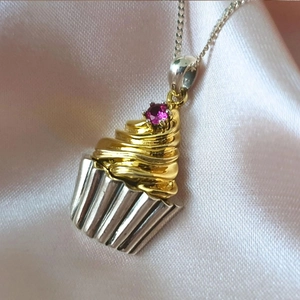 Close-up of a 18k gold-plated cupcake pendant necklace with a pink zircon stone