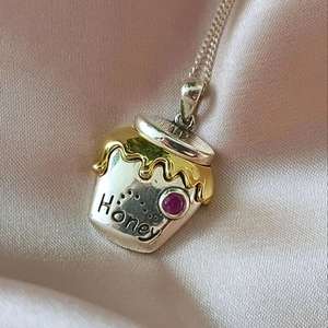 Macro shot of silver honey pot necklace with gold drip detail and pink stone inlay