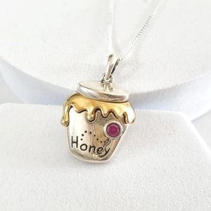 Detailed view of Honey pot pendant necklace featuring gold enamel and red zircon stone