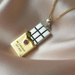Macro shot of gold and silver chocolate bar pendant with red gemstone and engraving
