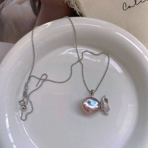 Macro detail of fish-shaped baroque pearl pendant with silver tail on beaded chain