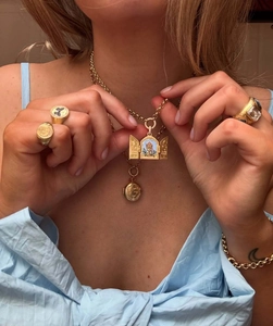 Close-up of luxury gold stainless steel jewelry set including locket necklace and rings