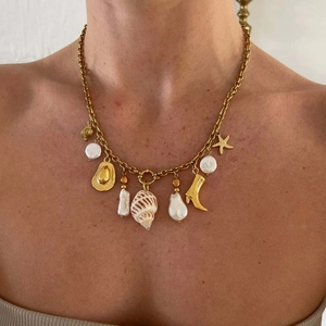 Détail du collier doré avec perle baroque, étoile de mer et pendentifs coquillages