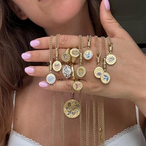 Detailed view of layered gold necklaces with enamel pendants and diamond rings on model