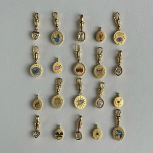 Detail of colorful enamel and zircon pendants with bird and floral patterns on gold plating