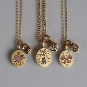 Detailed view of three gold necklaces featuring pink enamel charms and diverse gemstones