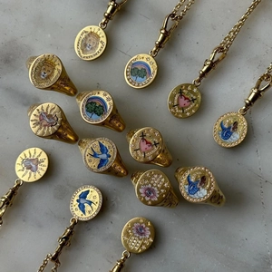 Macro detail of gold-plated enamel jewelry with crown lion and bird motifs and crystals