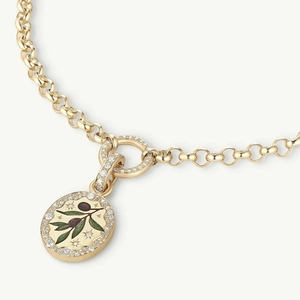 Macro shot of gold necklace featuring olive leaf pendant with pavé set diamonds and enamel