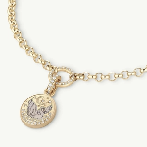 Macro detail of gold coin pendant featuring swan and crescent moon with inlaid stones
