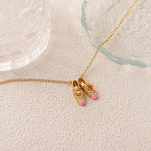 Elegant pink ballet slipper necklace with sparkling diamonds on a stone background