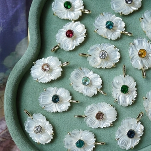 Vue détaillée de pendentifs fleurs en zircon coloré sur un présentoir en velours vert