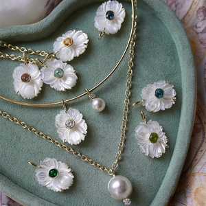 Collier fleur blanche avec pierres de naissance et perles sur plateau vert