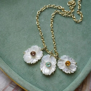 Détail de trois pendentifs fleurs sculptées avec pierres de couleur sur chaîne dorée