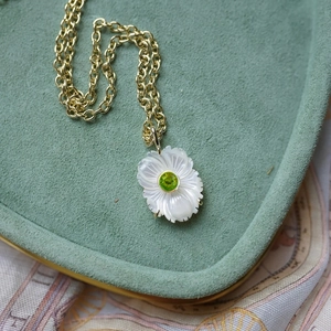 Détail du collier fleur en nacre avec zircon vert et sertissage en métal doré