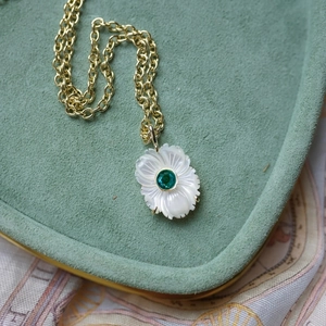 Détail du pendentif fleur avec pétales en nacre blanche et gemme verte sur collier doré