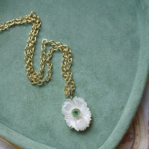 Détail du pendentif fleur en nacre blanche avec pierre verte sur chaîne dorée