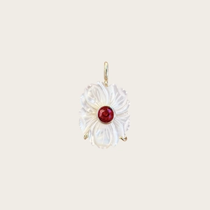 Gros plan du pendentif fleur en nacre blanche avec zircon rouge et dorure