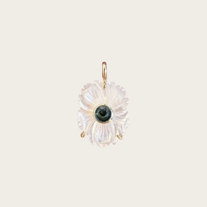 Vue détaillée du pendentif fleur blanche avec gemme verte et monture en métal doré