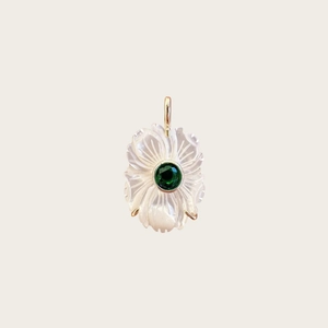 Détail d'un pendentif fleur en nacre blanche avec pierre verte et monture dorée