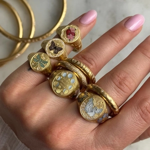 Macro detail of retro enamel signet rings with vintage butterfly and moon patterns