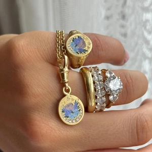 Macro shot of 18K gold signet ring with floral engraving and diamond band ring layering