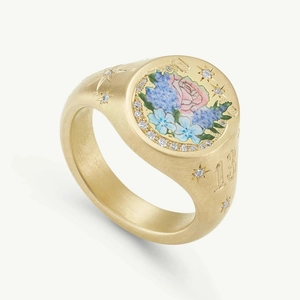 Macro detail of matte gold signet ring with floral enamel and engraved number 13