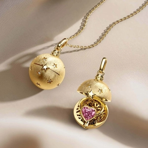 Collar de medallón de esfera dorada con estrellas y cristal de corazón rosa dentro