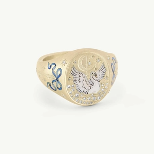 Detailed macro of golden signet ring with white swan, moon, and blue enamel bow