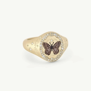 Close-up of golden seal ring with butterfly center and sparkling rhinestone halo