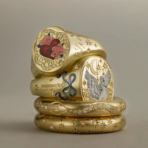 Stack of four 18K gold titanium rings with enamel seal patterns and diamond accents