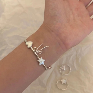 Süßes Silberarmband mit Herz, Stern und Schleifenanhängern getragen am Handgelenk