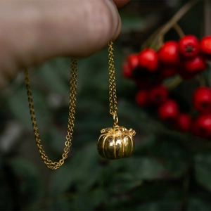 Vista dettagliata di una collana con ciondolo a zucca dorata e incisioni metalliche