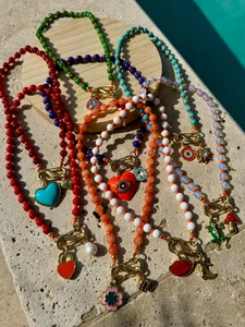 Détail de colliers de perles colorés avec charms œil et cœur sur un plateau en pierre