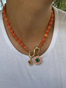 Détail du collier de perles colorées avec fermoir mousqueton doré et charms trèfle