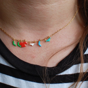 Detail of creative gold necklace with colorful enamel laundry charms on model