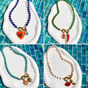 Détail de colliers de perles avec porte-bonheur œil et cœur sur plateau céramique