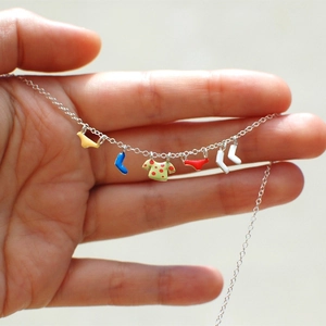 Detail of creative silver necklace featuring colorful enamel clothes and socks charms