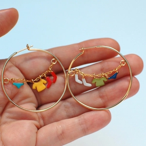 Detailed close-up of gold hoop earrings featuring colorful enamel laundry charms on tiny chains
