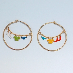 Detail of gold hoop earrings with colorful laundry pendants including socks and t-shirts