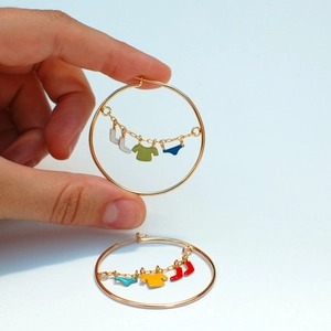 Macro shot of gold-plated hoop earrings with colorful oil-dripping laundry pendants